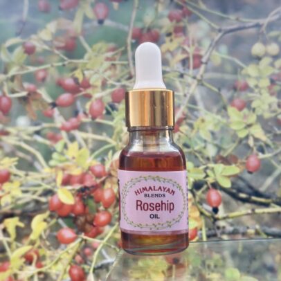 Cold-pressed rosehip oil bottle with Himalayan rosehips in the background Organic rosehip oil made from wild rosehips collected in Chamba Valley Dropper bottle of rosehip facial oil placed on a natural wooden background Handcrafted rosehip oil for skin – pure and chemical-free